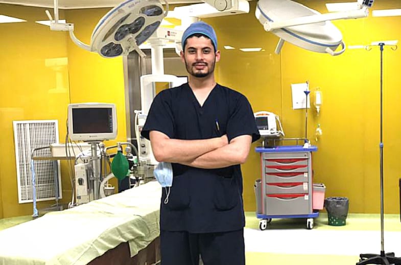 a man in scrubs and hat standing in a room with medical equipment
